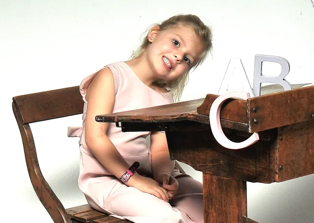 Mädchen an der Schulbank mit Holzbuchstaben ABC